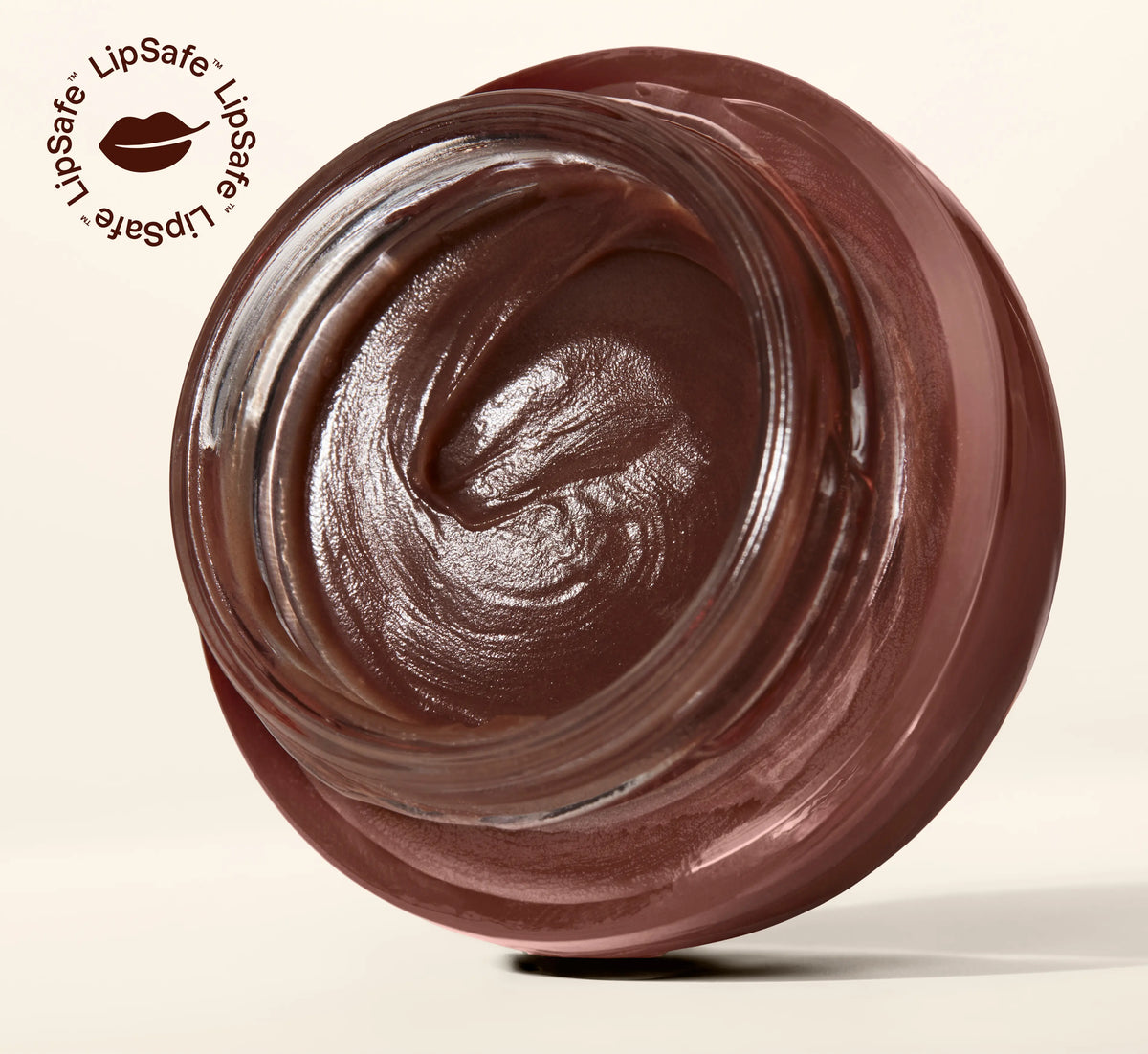 An open round jar filled with glossy, dark brown whipped cream or body butter, photographed on a clean light beige background. A small LipSafe logo with a lip icon appears in the upper left corner.